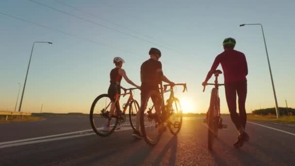 夕方の長距離ライドの後に自転車で歩くスポーツウェアや安全ヘルメットの若い白人のバックビュー 夏の夕日の美しい景色 — ストック動画