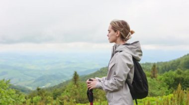 Sırt çantalı, gezen, yürüyüş yapan sarışın kadın turistin yan görüntüsü. Tepede duran, esinti yapan, dağların güzelliğine hayran genç bir kadın. Turizm ve yürüyüş kavramı.