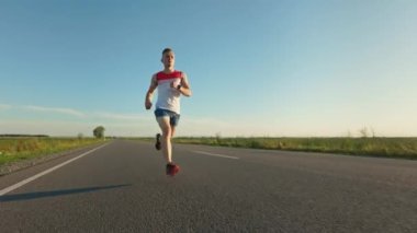 Güçlü bir erkek sporcunun ön görüntüsü, yaz aylarında antrenman dayanıklılığı. Spor giyimli ve spor ayakkabılı bir adam maratona katılıyor, egzersiz yapıyor. Sağlık ve spor kavramı.