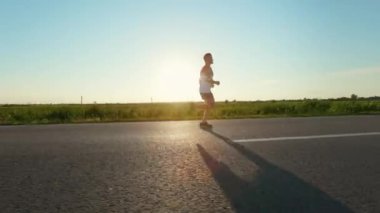 Sporcunun koşuşunun yan görüntüsü, sıcak yaz mevsiminde antrenman dayanıklılığı. Genç, erkek atlet koşuyor, antrenman yapıyor, yolda egzersiz yapıyor. Spor anlayışı ve sağlıklı yaşam tarzı.