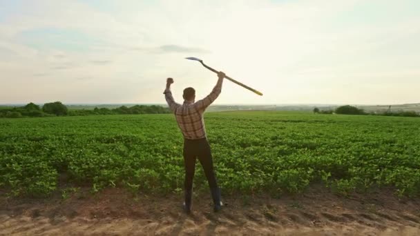 回顾快乐的农民站在那里 举起手来 拿着铁锹 在农村的土地上干活的年轻男性 看着苗木 种植植物和农业的概念 — 图库视频影像