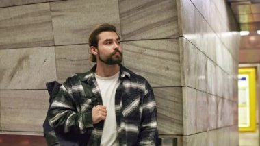 Sıradan kıyafetler giyen yakışıklı bir adam metroda dikiliyor. Bekleyen yorgun yakışıklı adam, sırt çantası taşıyor, yan bakıyor, düşünüyor. Toplu taşıma kavramı.