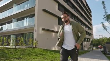 Ciddi, meşgul bir adamın caddede yürümesi, elinde tutması, akıllı telefon kullanması. Sırt çantalı esmer erkek, şık kıyafetler giyiyor. Kentsel yaşam tarzı kavramı.