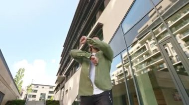 Sakallı esmer adamın ön görüntüsü. Kulaklıkla müzik dinliyor, dans ediyor. Yakışıklı erkek şık giyiniyor, günlük kıyafetler giyiyor, eğleniyor, gülümsüyor. Kentsel yaşam tarzı kavramı.