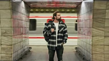 Toplu taşıma aracıyla seyahat eden yakışıklı, esmer adamın ön görüntüsü. Erkek turist metroda duruyor, bekliyor, el ele tutuşuyor. Toplu taşıma kavramı.