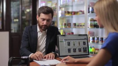 Side view of glad business partners making agreement with each other. Man signing contract, document, shaking hands with blonde woman in office at table. Concept of business.