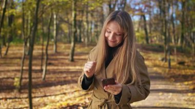 Tarz sahibi, şık giyinen, parkta yürüyen genç bir bayan. Çekici bir kadın ayakta, müzik dinliyor, dans ediyor, gülümsüyor. Modern yaşam kavramı.
