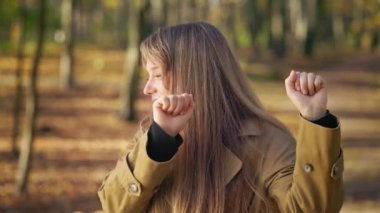 Front view of happy, cheerful lady walking in park, standing, dancing, enjoying. Beautiful, young female smiling, wearing fashionable clothes. Concept of happiness and joy.