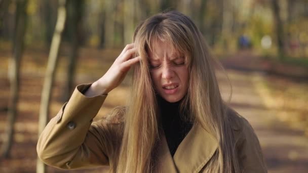 公園に立って疲れた女性の側のビューでは 頭に触れる かなり若い女性は頭痛がし 目を閉じて 疲れて 動揺し 失望した 誠実な感情の概念 — ストック動画
