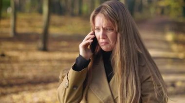 Side view of young, stylish woman wearing fashionable clothes, talking on phone. Attractive female crying, quarreling, raising hands, angry, irritated. Concept of modern living.