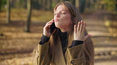 Side view of angry, irritated woman walking, standing in park. talking on phone. Pretty, young female quarreling, crying, wearing fashionable coat. Concept of modern lifestyle.