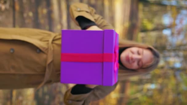 前景色迷人 年轻的女士拿着礼品盒 高兴的女人看着相机 秋天在公园里散步 幸福与欢乐的概念 — 图库视频影像