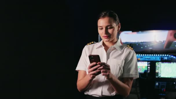 かなり女性のパイロットスチュワーデスの正面図は キャビンに立って 休憩している 女性の制服を着て スマートフォンを使用して 航空及び航空機の概念 — ストック動画