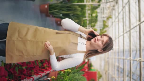 Çiçekçi Kadın Önlük Giyip Serada Dikiliyor Güzel Bayan Akıllı Telefonda — Stok video