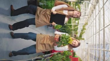 Dans eden, şarkı söyleyen, eğlenen iki neşeli kadın çiçekçinin yan görüntüsü. Pozitif kadınlar, çiçekçiler, serada çalışmak, bitkilerle ilgilenmek. Mutluluk ve keyif kavramı.