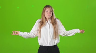 Genç, sarışın bir kadının stüdyoda şaşkın bir şekilde duruşu. Güzel bir kadın resmi kıyafetler giyiyor, ellerini uzatıyor ve soruyor. Yeşil stüdyo arka planında izole edilmiş..