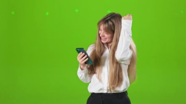 Stüdyoda akıllı telefon kullanan neşeli genç bir bayan görüyorum. Güzel, sarışın bir kadın ekrana bakıyor. Mutluluk kavramı ve samimi duygular.