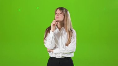 Stüdyoda dikilen, elini kaldıran, eğilen sarışın güzel bir kadının yan görüntüsü. Mutlu, genç bayan gülümsüyor, hayal kuruyor, düşünüyor, hayal ediyor. Yeşil stüdyo arka planında izole edilmiş..