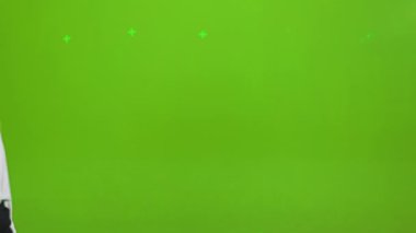 Sarışın genç bir bayanın stüdyoda yürümesi, ayakta durması, poz vermesi. Resmi giysiler giymiş, kameraya bakan mutlu, güzel bir kadın. Yeşil stüdyo arka planında izole edilmiş..