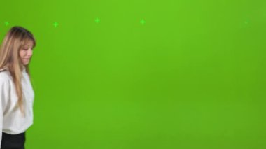 Yürüyen, ayakta duran, el sallayan, işaret eden, gülümseyen neşeli bayanın yan görüntüsü. Çekici, genç bir bayan kameraya bakıyor, beyaz gömlek giyiyor. Mutluluk kavramı ve samimi duygular.