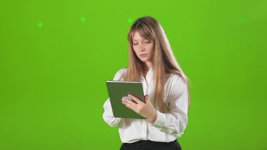 Stüdyoda tablet kullanan konsantre ve odaklanmış bir kadının yan görüntüsü. Genç, sarışın, meşgul kadın kayıyor, okuyor, kameraya bakıyor. Modern şehir yaşam tarzı kavramı.