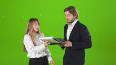 İş ortaklarının stüdyoda dikilip, konuşup, tartıştıklarını görmek. Güzel bir kadın ve resmi kıyafetler giyen yakışıklı bir adam. Yeşil stüdyo arka planında izole edilmiş..