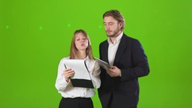 Stüdyoda elinde dosyalarla bekleyen iş ortaklarının yan görüntüsü. Kadın ve erkek resmi kıyafetler giyer, konuşur, gösteriş yaparlar. Yeşil stüdyo arka planında izole edilmiş..