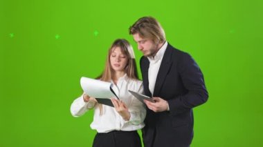 Stüdyoda çalışan, konuşan, tartışan başarılı iş ortaklarının yan görüntüsü. Güzel bir kadın ve yakışıklı bir erkek klasör ve tablet tutuyor. İş ilişkileri kavramı.
