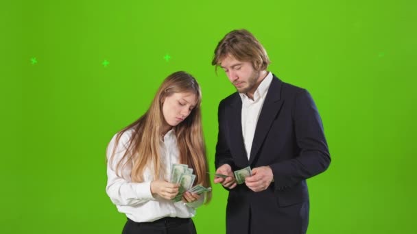 若い女性と男性の公式服を着てのサイドビューでは お金を数える スタジオに立つ成功した実業家と実業家 緑のスタジオを背景に孤立 — ストック動画