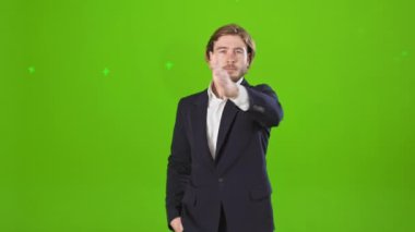 Yakışıklı bir erkek, kameraya bakıyor, poz veriyor. Genç adam kostüm ve gömlek giyiyor, kaldırıyor, elini sallıyor. Modern, kentsel yaşam tarzı kavramı.