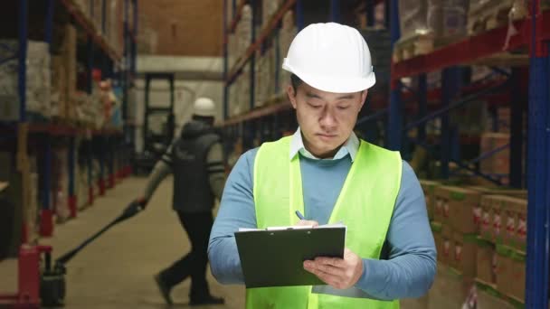 Geconcentreerde Aziatische Man Veiligheidshelm Vest Notering Klembord Tijdens Inventaris Voorraadhuis — Stockvideo