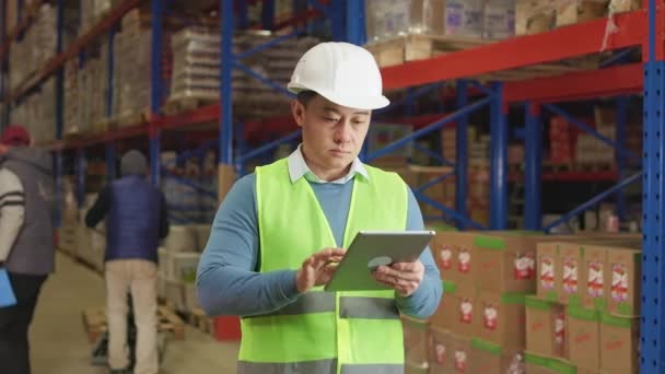 Asian Warehouse Manager Texting Digital Tablet While Male Workers Loading — Stock Video