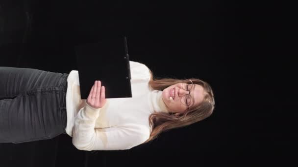 穿着休闲装和眼镜的女企业家在黑色舞台上做着大拇指向上的手势 白种人女人戴耳机说话 用剪贴板记笔记 — 图库视频影像