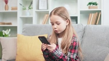 Kafkasyalı liseli bir kızın yumuşak koltukta otururken akıllı telefondan daktilo yazması. İlerici çocuk sosyal medyayı arkadaşlarıyla sohbet etmek ve medya dosyalarını paylaşmak için kullanıyor. Çocuklar ve teknoloji.