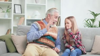 Güzel küçük çocuk evde tatilin tadını çıkarıyor ve büyükbabasıyla harika vakit geçiriyor. Torunuyla birlikte oynayıp beşlik çakan duygusal büyükbaba..