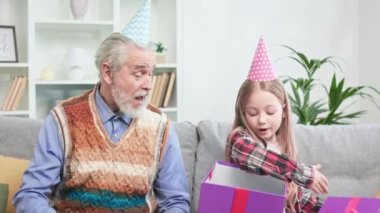 Sevgi dolu büyükbaba tarafından sunulan muhteşem hediye kutusunu açan inanılmaz sevimli kız. Doğum günü için VR kulaklığı alan heyecanlı bir çocuk. Büyükbaba ve torun arasındaki kırılmaz bağ kavramı.