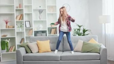 Her gün çıplak ayakla kanepede zıplayan ve hafta sonu evde boş vakit geçirmekten hoşlanan okul kızı. Küçük mutlu çocuk komik bir aile aktivitesine dahil oldu..