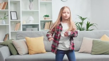 Kafkasyalı sanatçı kız hızlı dans ediyor sonra da kanepede zıplıyor ve düşüyor. Sıradan giyinmiş, dinamik bir çocuk evde eğleniyor ve okul tatillerinin tadını çıkarıyor. Evde aktif boş zaman aktivitesi kavramı.