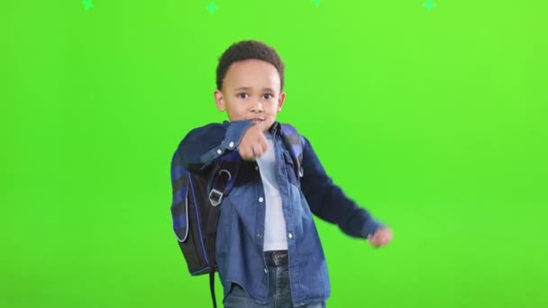 可爱的男生蓝色的包 显示大拇指在工作室 穿着休闲装 摆出姿势 对着镜头微笑 被绿色隔离的非洲裔美国男生的前景 学校的概念 — 图库视频影像