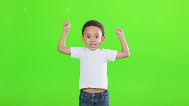 快乐的男孩儿穿着休闲装 从欢乐中举起胳膊在工作室里 从正面看快乐的非洲裔美国男孩表现出得意洋洋的姿态 孤立在绿色工作室的背景下 情绪的概念 — 图库视频影像