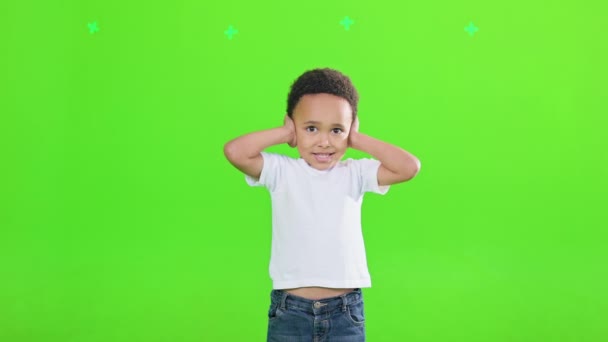 可爱的非洲裔美国小男孩捂住耳朵 不让工作室里的噪音干扰 无言学童身穿白衬衫 手放在耳朵上 与绿色背景隔离的前视图 情绪的概念 — 图库视频影像