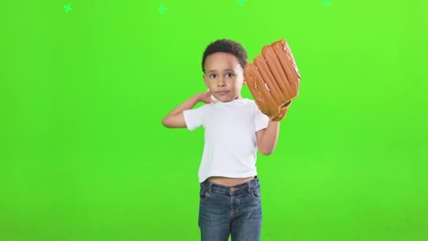 可爱的焦点非洲裔美国男孩穿着棒球手套扔球在工作室 眼前是一个严肃的小男孩穿着白色T恤打棒球 被绿色隔离 体育概念 — 图库视频影像