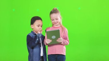 Mutlu odaklı çocuklar kapalı alanda dijital tablet ekranını kaydırıyor. Gündelik giysiler içinde gülümseyen, modern dokunmatik ped kullanan, yeşilde izole edilmiş çok ırklı çocukların ön görüntüsü. Teknoloji konsepti.