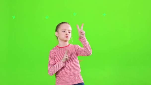 时髦漂亮的小女孩跳舞 在工作室里跳 在运动 前视自信的女孩戴着耳罩玩乐 表现出胜利的姿态 在绿色上孤立无援 闲暇时间的概念 — 图库视频影像