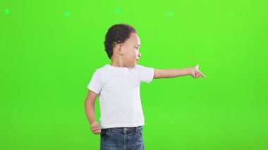 Gülümseyen erkek çocuk stüdyonun yanındaki boşluğu işaret ediyor. Heyecanlı Afrikalı Amerikalı küçük çocuğun yeşil arka planda izole edilmiş işaret parmağıyla el hareketi göstermesi ön planda. El kol hareketi kavramı.