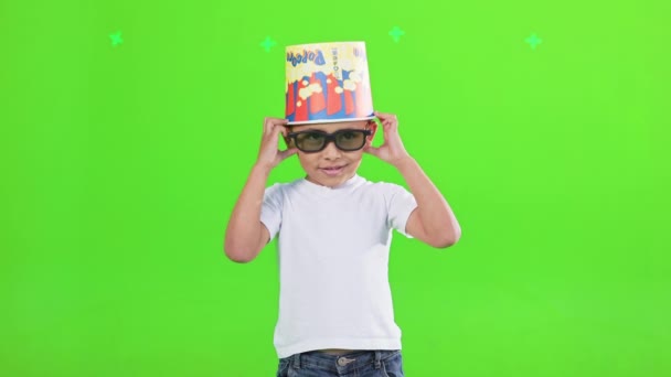 滑稽的小男孩戴着太阳镜 头上顶着一个装爆米花的大桶 面带微笑 酷酷的非洲裔美国小孩跳舞 对着镜头笑 被绿色隔离 生活方式概念 — 图库视频影像