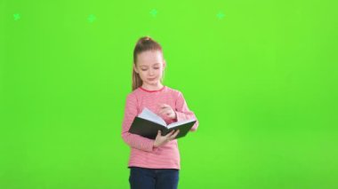 Odaklanmış küçük kız kitap okuyor, sayfaları çeviriyor, hareket halinde. Stüdyoda dikilirken günlük kıyafetler giyen beyaz kadın çocuk ön planda. Eğitim kavramı.