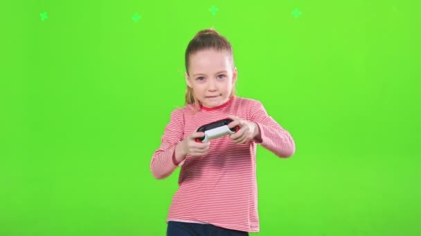 白人小女孩在工作室里兴致勃勃地玩电子游戏 带着操纵杆的专注的女孩 娱乐性的 绿色背景的隔离 运动中 娱乐的概念 — 图库视频影像