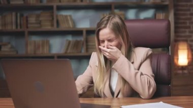 Kafkasyalı sarışın kadın iş sırasında hapşırıyor ve ağzını eliyle kapatıyor. Ofiste dijital alet kullanan ve kameraya gülen zarif giyimli bayan çalışanlar..