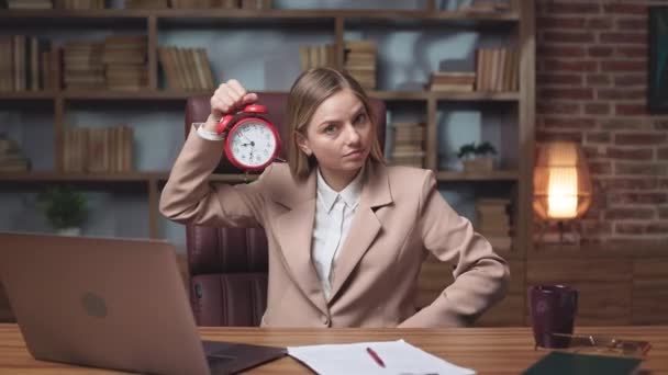 同僚に仕事が遅れていることを警告する怒っている会社の取締役 若い女性は赤い目覚まし時計を実証し 時間通りに時間通りにオフィスに来てほしい — ストック動画